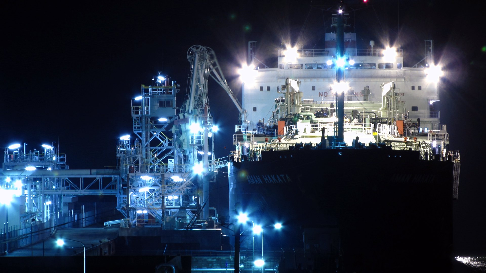 An LNG carrier alongside a lit loading terminal at night
