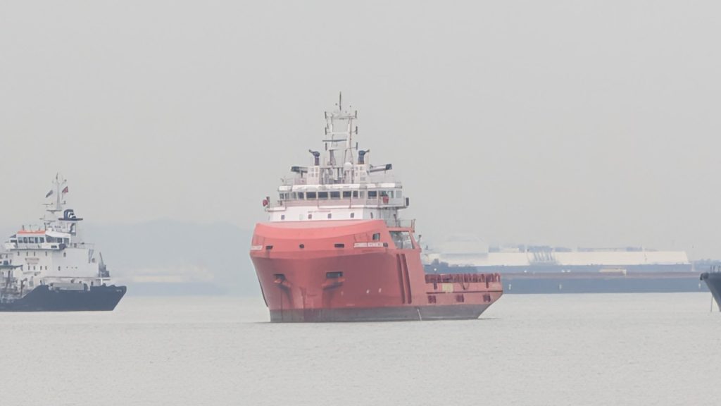 An offshore support vessel lying at anchor off a port